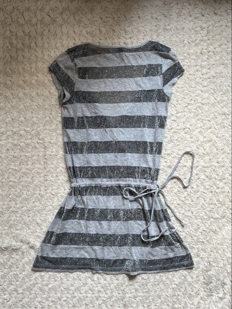 Divided by H&M Grey Striped Sparkle Tie Top (Category: Dresses) located in Mandaluyong City. Submitted by namislounge (Listing ID 1466928545, Image 2). Description: Fits xs-small - Style: Grey & black striped wrap dress with subtle metallic silver sparkle - Design: V-neck front, short cap sleeves, adjustable drawstring waist - Fabric: Lightweight knit with stylish sheer panels on top - Made in Turkey - Condition: Great piece for casual nights out