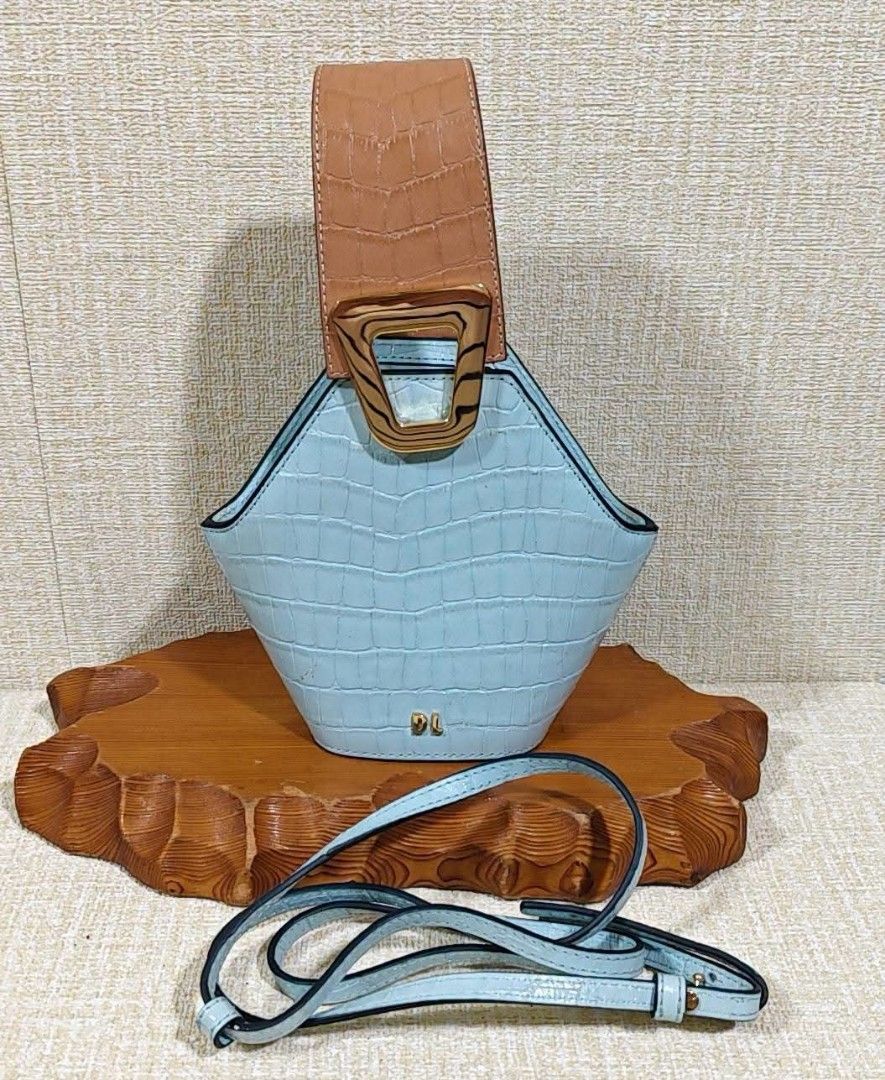 DL Two-Tone Crocodile Textured Bucket Bag with Strap (Category: Luxury Bags & Wallets) located in Manila. Submitted by boldfire_315559 (Listing ID 1466808970, Image 1). Description: - Style: Light blue and tan crocodile embossed bucket bag - Design: Unique trapezoid shape with structured top handle and geometric gold-tone buckle - Branding: Gold DL logo lettering on the front base - Versatility: Includes a matching detachable long shoulder strap 