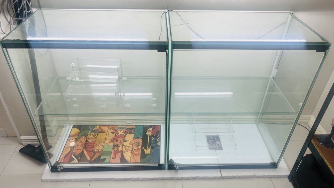 Double glass display cabinet with built-in lights (Category: Shelves, Cabinets & Racks) located in Caloocan City. Submitted by daddybhurr008.stone (Listing ID 1466919755, Image 1). Description: - Double glass display case measuring approx. 48" wide by 31" deep - Fully equipped with interior shelves, acrylic risers, and built-in LED light strips - Features a custom anime poster insert on the bottom shelf - Glass panels cleaned and inspected - Flaw