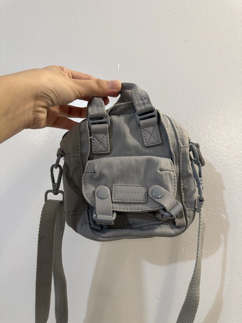 Doughnut Grey Mini Backpack Crossbody Bag (Category: Backpacks) located in Makati City. Submitted by cosmicfire.4ba272 (Listing ID 1466929349, Image 1). Description: - Brand: Doughnut - Type: Mini backpack style crossbody bag - Color: Grey - Features: Front flap pocket with branded patch and dual snap buttons, top grab handles, adjustable webbed shoulder strap, main zip compartment, and inner slip pocket - Flaws: Small reddish stain on the back e
