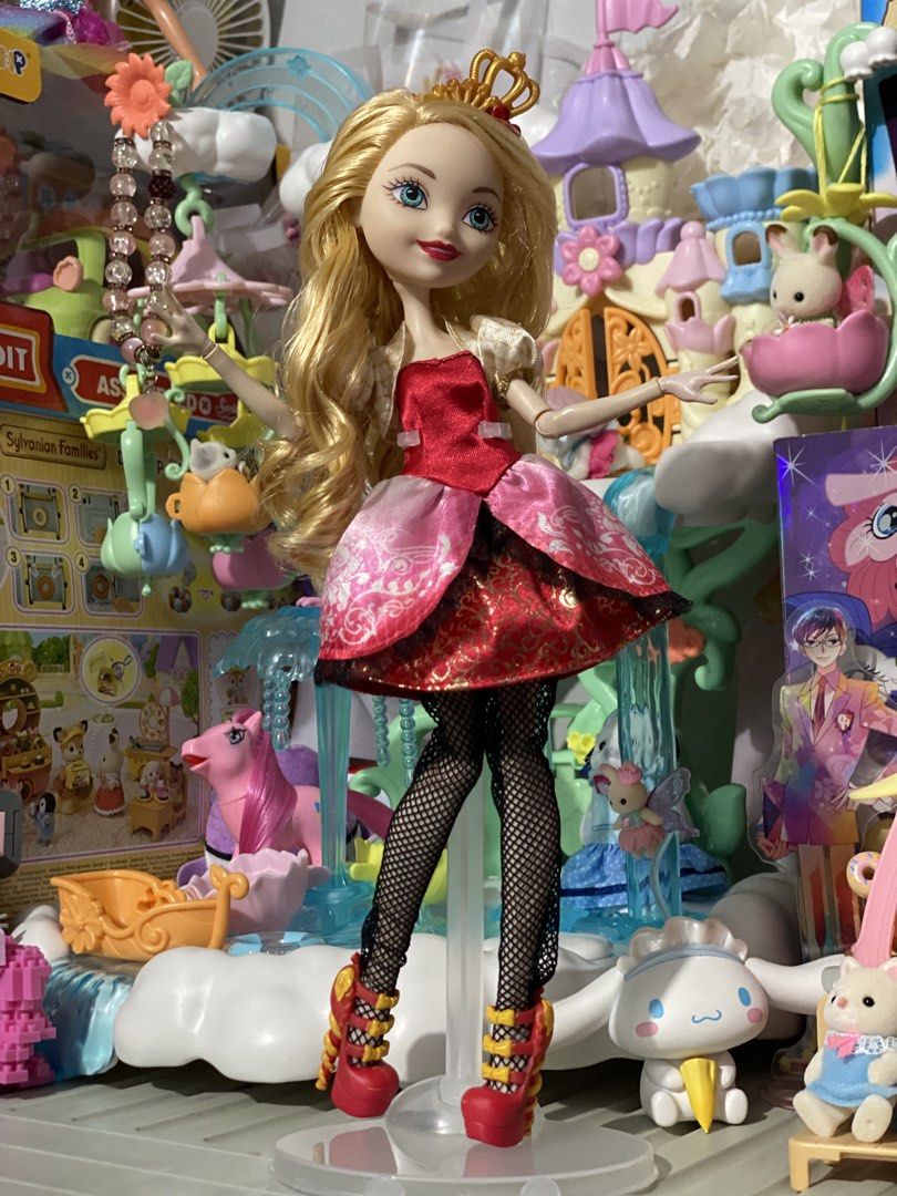 Ever After High Apple White Doll (Category: Kids Toys) located in Manila. Submitted by deniseeverafter (Listing ID 1466846297, Image 1). Description: - Character: Apple White from Ever After High - Hair & Face: Long blonde curled hair and blue eyes - Accessories: Gold crown headpiece and clear display stand included - Outfit: Red bodice, pink and red layered skirt, black fishnet tights, and red strapped heels - Condition: Clean hair and outfit, w