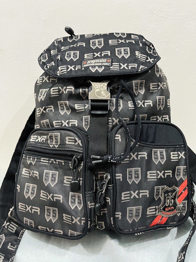 EXR Progressive Monogram Black Backpack (Category: Backpacks) located in Talisay. Submitted by cherylu (Listing ID 1466921070, Image 1). Description: EXR black backpack, monogram print all over with 55 logo patches. Front flap with a metal buckle closure plus twin front zip pockets with drawstrings. Inner lining has matching EXR pattern with a zipped pocket inside. Adjustable shoulder straps on the back. Sturdy hardware and durable fabric constru