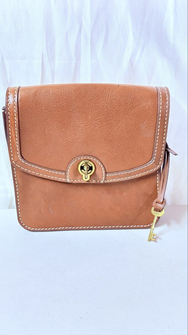 Fossil Brown Leather Crossbody Bag (Category: Cross-body Bags) located in Pateros City. Submitted by marifernandez (Listing ID 1466783532, Image 1). Description: Preloved Tan brown leather handbag by Original Fossil. Classic turn-lock closure on the front flap. Removable matching leather strap included. Signature little key charm hanging on the side. Inside is lined in brown fabric with a zippered pocket and slip pockets. Small Fossil logo stampe