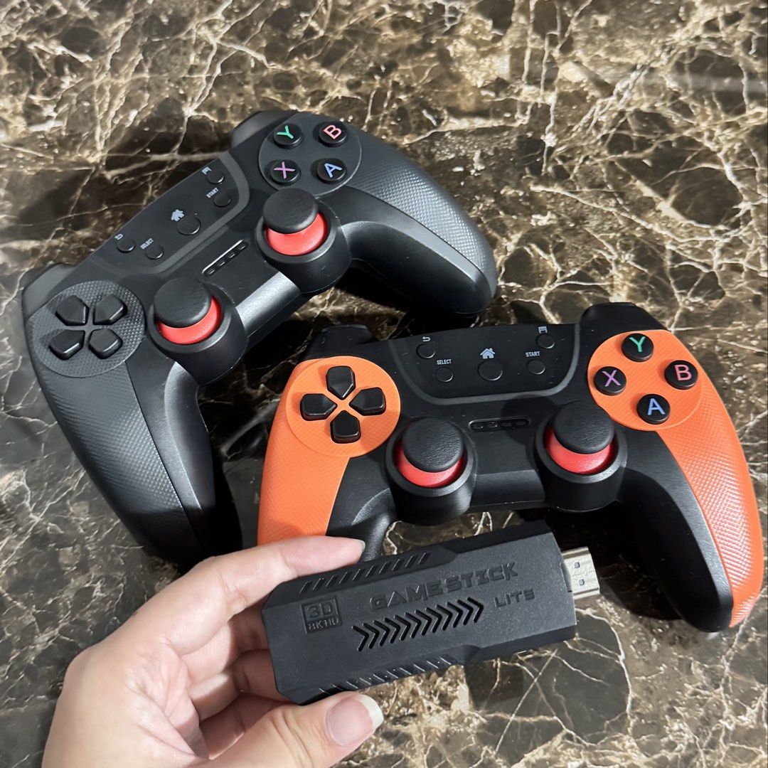 Game Stick Lite with Wireless Controllers (Category: Controllers) located in Rodriguez. Submitted by coleenlopezz (Listing ID 1466950850, Image 1). Description: - Complete retro gaming setup: includes HDMI game stick and 2 wireless controllers - Unique controller design: 1 fully black with red thumbsticks, 1 featuring bright orange grips - Plug-and-play: plugs directly into your TV's HDMI port for instant gaming - Game library: packed with classi