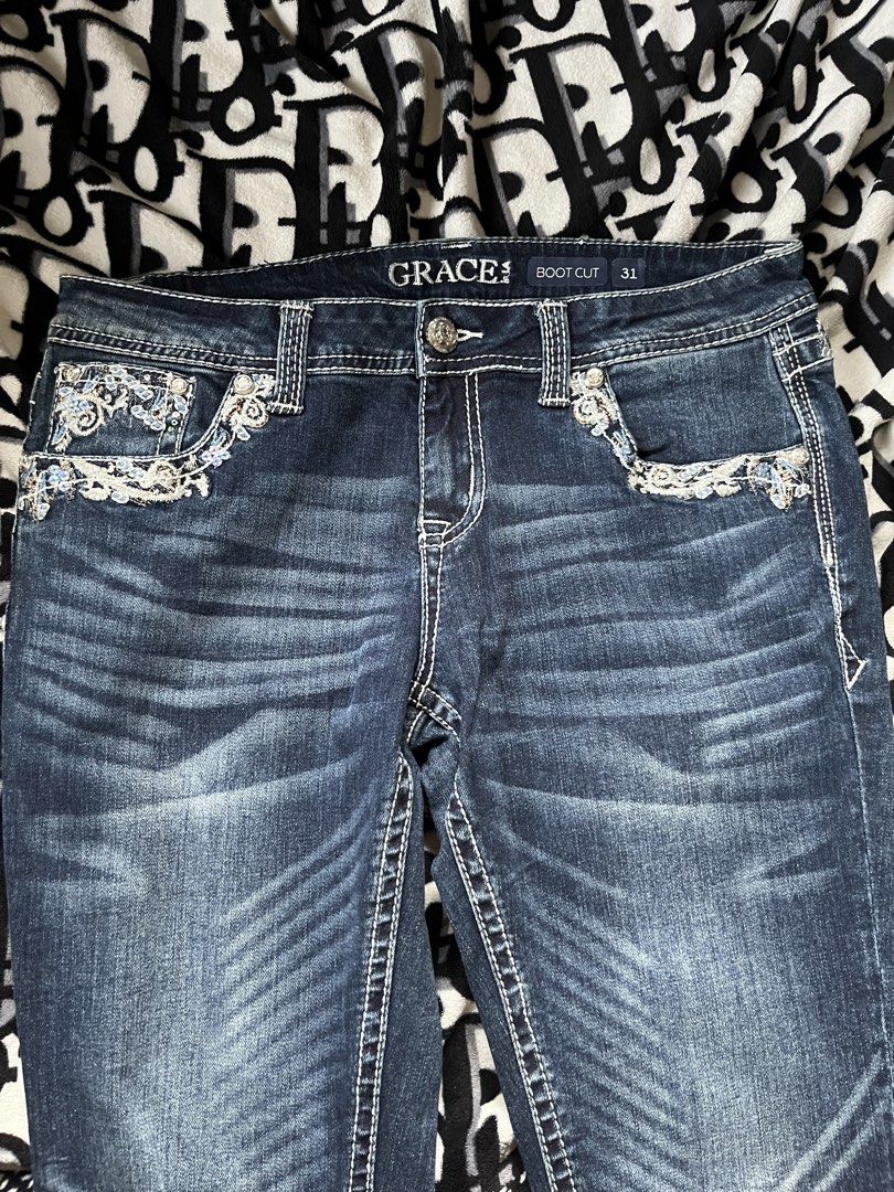Grace in LA Boot Cut Jeans Size 31 (Category: Jeans) located in Silang. Submitted by kristan.asian (Listing ID 1466901033, Image 3). Description: - Brand: Grace in LA - Style: Boot cut denim / Y2K Western - Size: Tagged size 31 - Wash: Dark blue - Details: Intricate embroidery and rhinestones on front pockets and back yoke - Back Pockets: Distressed embroidery with heavy sparkle embellishments - Stitching: Classic contrast white stitching through