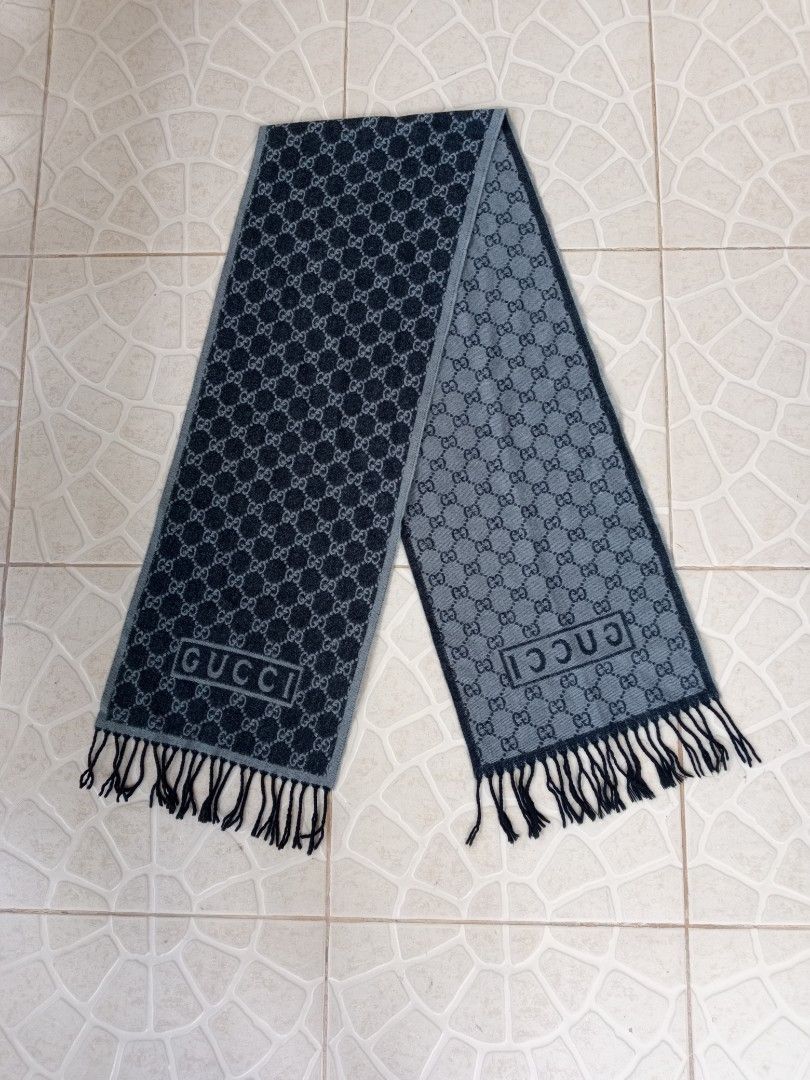 Gucci GG Monogram Reversible Scarf with Fringe (Category: Scarves) located in Liloan. Submitted by dnznoon31 (Listing ID 1466857041, Image 1). Description: - Brand: Gucci - Design: Classic GG monogram, reversible dark and light grey - Details: Boxed Gucci logo near the ends, finished with black fringe tassels - Material: Warm wool blend - Condition: Excellent - Dimensions 65 x 11.5 inches - Perfect for chilly weather and daily styling.