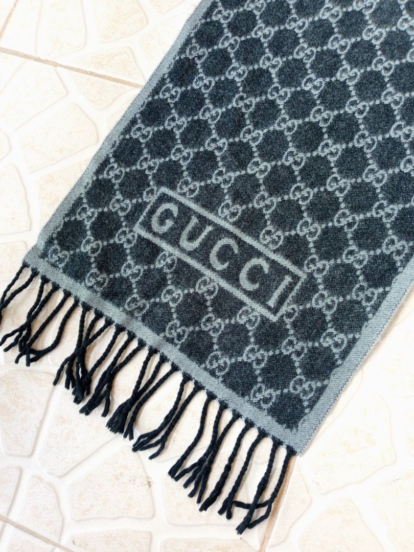 Gucci GG Monogram Reversible Scarf with Fringe (Category: Scarves) located in Liloan. Submitted by dnznoon31 (Listing ID 1466857041, Image 2). Description: - Brand: Gucci - Design: Classic GG monogram, reversible dark and light grey - Details: Boxed Gucci logo near the ends, finished with black fringe tassels - Material: Warm wool blend - Condition: Excellent - Dimensions 65 x 11.5 inches - Perfect for chilly weather and daily styling.