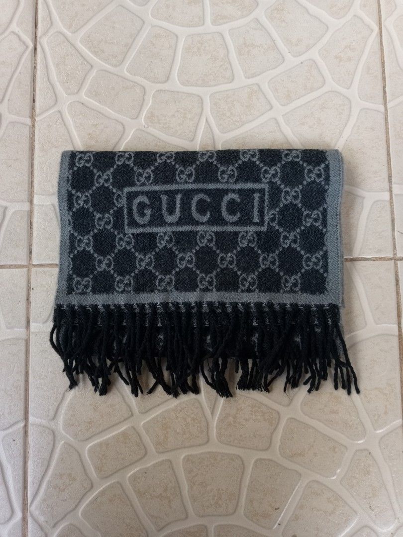 Gucci GG Monogram Reversible Scarf with Fringe (Category: Scarves) located in Liloan. Submitted by dnznoon31 (Listing ID 1466857041, Image 3). Description: - Brand: Gucci - Design: Classic GG monogram, reversible dark and light grey - Details: Boxed Gucci logo near the ends, finished with black fringe tassels - Material: Warm wool blend - Condition: Excellent - Dimensions 65 x 11.5 inches - Perfect for chilly weather and daily styling.