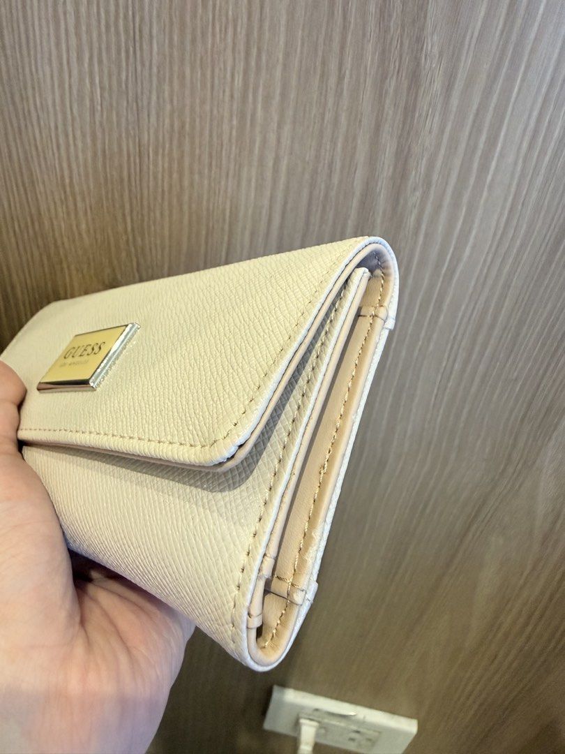 Guess Cream Long Wallet with Card Slots (Category: Wallets & Card holders) located in Manila. Submitted by angelcurated (Listing ID 1466809398, Image 3). Description: - Brand: Guess - Color: Cream (neutral tone that matches any outfit) - Material: Premium leather-textured finish - Hardware: Silver-tone front logo plate - Closure: Smooth snap button closure - Exterior: Convenient back zipped coin pocket - Interior: Multiple card slots and spacious