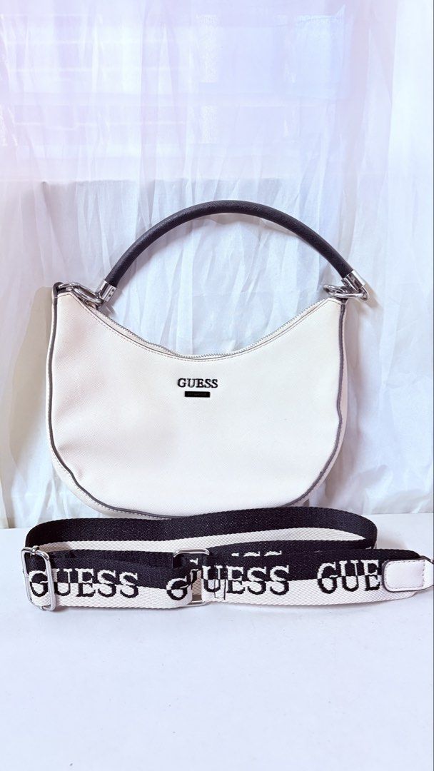 Guess Cream Shoulder Bag with Interchangeable Straps (Category: Shoulder Bags) located in Pateros City. Submitted by marifernandez (Listing ID 1466783771, Image 1). Description: Original preloved Guess cream-colored hobo bag with structured design. Silver hardware and black trim details. Top zipper closure opens to branded lining with internal pockets. Includes both a short dark top handle and a thick, branded canvas crossbody strap. Clean interi