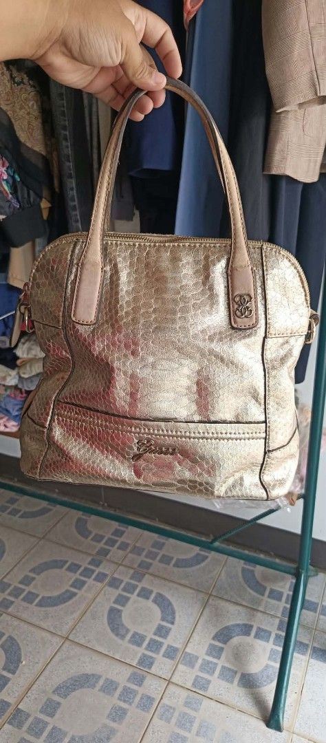 Guess Gold Metallic Snake Print Handbag (Category: Luxury Bags & Wallets) located in Dimasalang. Submitted by tinzstory (Listing ID 1466967980, Image 1). Description: Brand: GUESS Style: Metallic Gold Snakeskin Dome Satchel / Handbag Interior: Clean floral signature lining with zipper and slide pockets (No rips or major stains). Hardware: Shiny gold-tone hardware and iconic GUESS logo charms are fully intact. ⚠️ Condition Notes (Please Read Befor