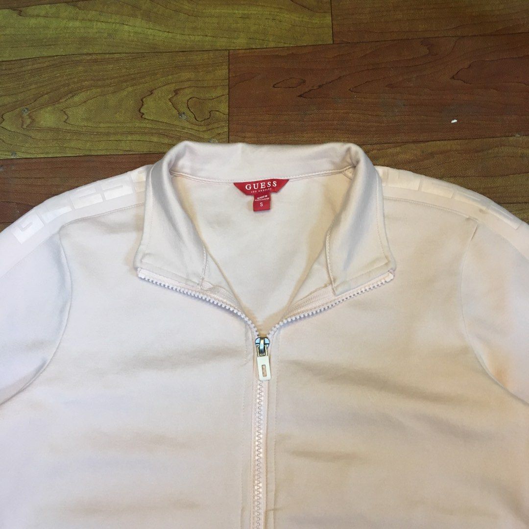 Guess light pink zip-up track jacket size S (Category: Coats, Jackets and Outerwear) located in Zamboanga. Submitted by yuriwantscreampie (Listing ID 1466874887, Image 2). Description: - Brand: Guess - Color: Light pink - Size: Small - Design: Full zip front with high collar - Details: Tape detail with printed branding along both sleeves - Features: Ribbed cuffs and hem, two front welt pockets - Authenticity: Red Guess tag inside at the collar.