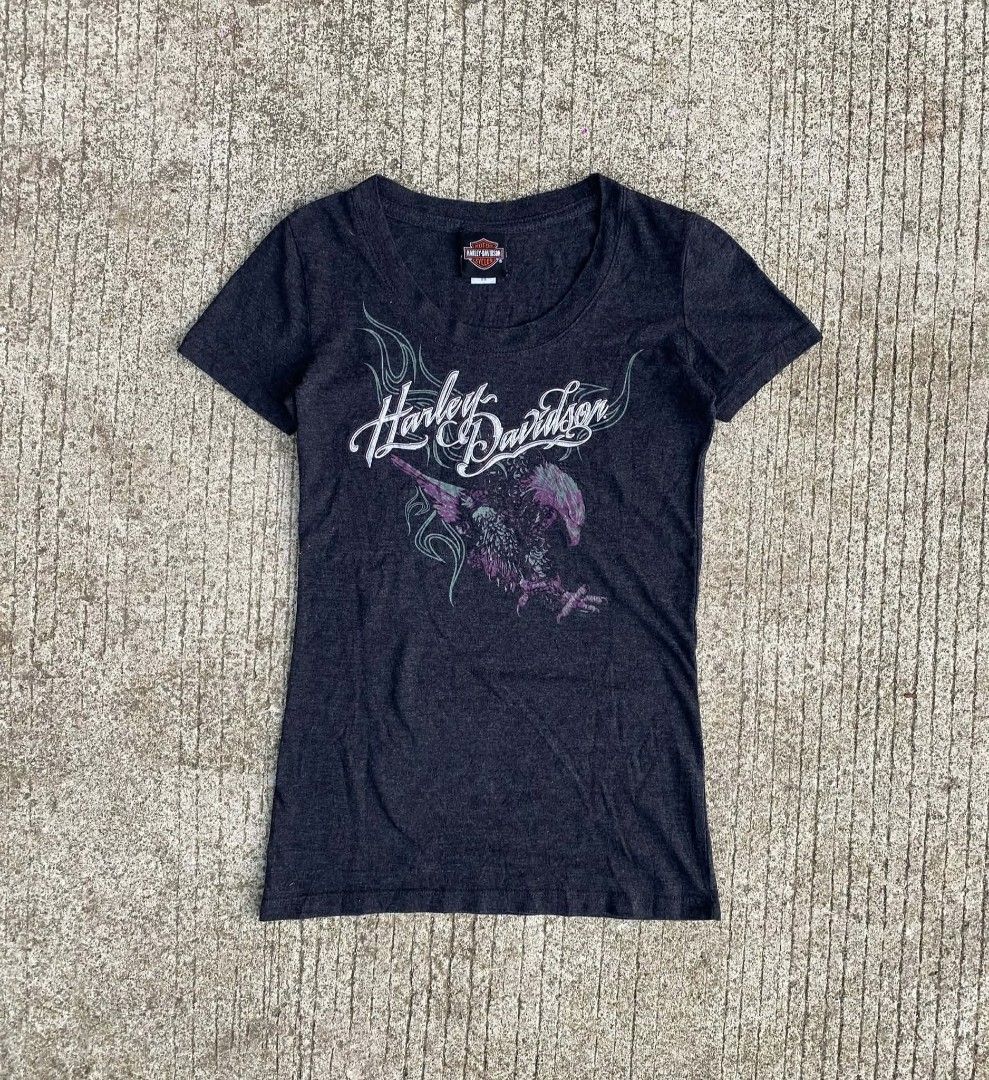 Harley-Davidson Eagle Graphic T-Shirt (Category: Tshirts & Polo Shirts ) located in Sipalay. Submitted by yon.thrifter (Listing ID 1466774049, Image 1). Description: - Brand: Harley-Davidson (Bravado International Group tag) - Color: Dark grey heather - Size: XS - Neckline: Scoop neck with short sleeves - Design: White script logo with green tribal flames and purple eagle graphic - Condition: Excellent, ready to wear - Perfect for casual streetwe