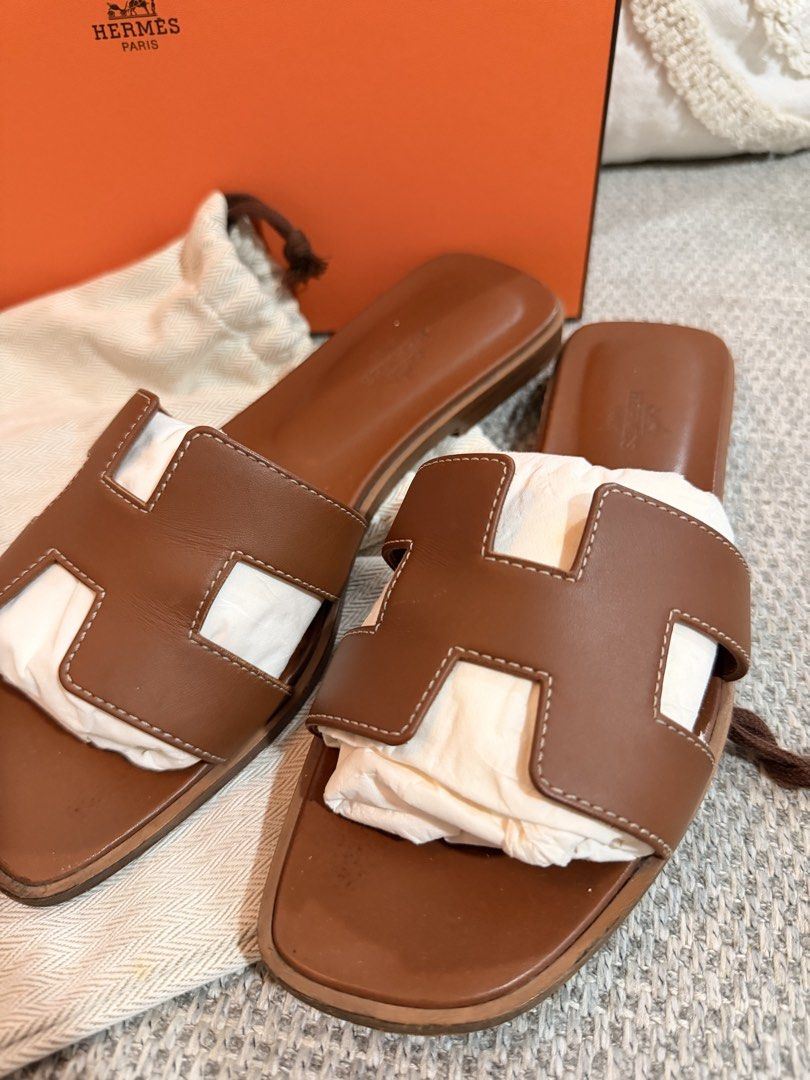 Hermes Oran Sandals Brown (Category: Flats & Sandals) located in San Pedro. Submitted by kathlynaviles_ (Listing ID 1466946314, Image 2). Description: - Authentic Hermes Oran Sandals in a rich brown leather colorway - Features the iconic cutout H strap design with a comfortable flat slide style - Stamped Hermès Paris on the footbed for guaranteed authenticity - Comes with complete inclusions: original orange box and dust bags - Perfect luxury eve