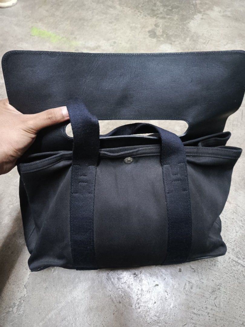 Hermès Black Canvas Leather Tote Bag (Category: Tote Bags) located in Cabatuan. Submitted by penthegreat (Listing ID 1466784827, Image 3). Description: - Brand: Hermès - Material: Black canvas body with premium leather flap top and double handles - Hardware: Silver-tone with engraved branding on snap buttons - Interior: Spacious layout with multiple pockets and convenient key clips - Style: Classic, versatile dark colorway ideal for everyday esse