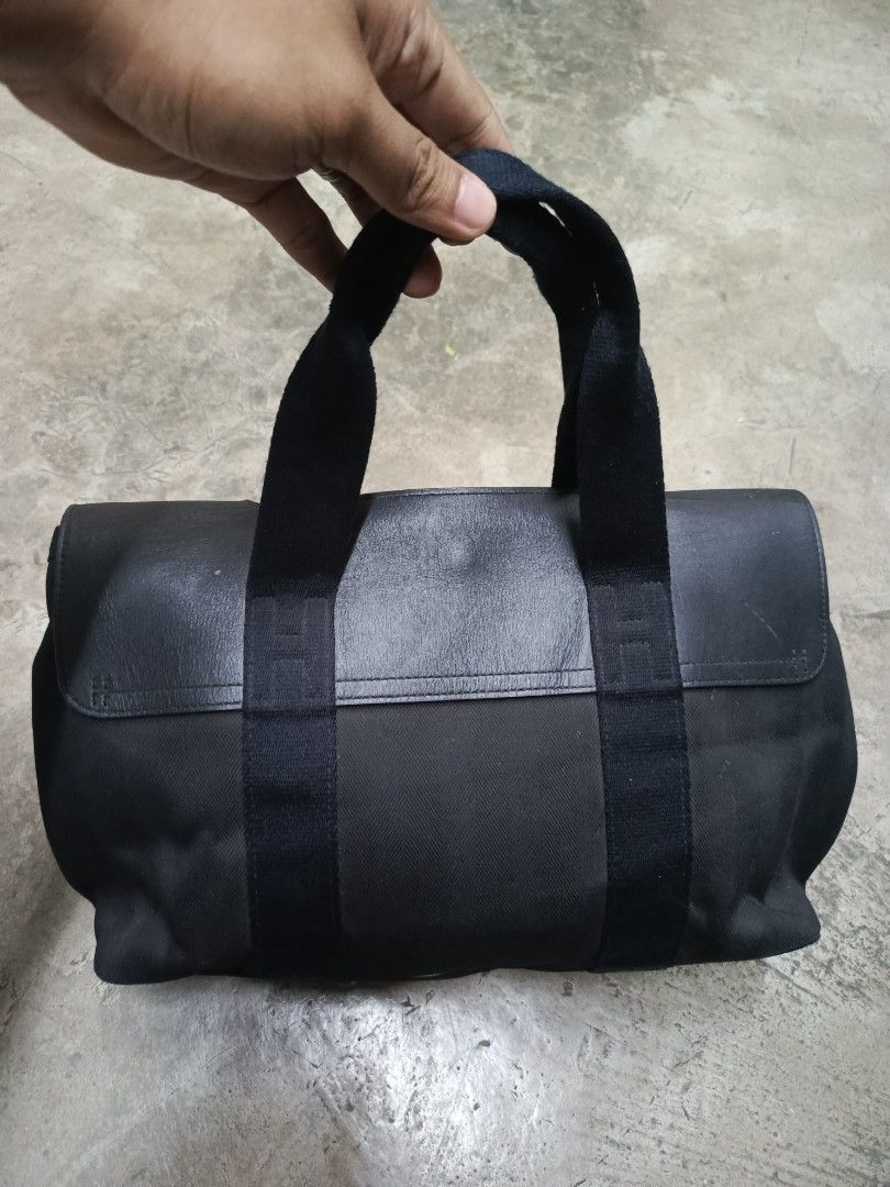 Hermès Black Canvas Leather Tote Bag (Category: Tote Bags) located in Cabatuan. Submitted by penthegreat (Listing ID 1466784827, Image 2). Description: - Brand: Hermès - Material: Black canvas body with premium leather flap top and double handles - Hardware: Silver-tone with engraved branding on snap buttons - Interior: Spacious layout with multiple pockets and convenient key clips - Style: Classic, versatile dark colorway ideal for everyday esse