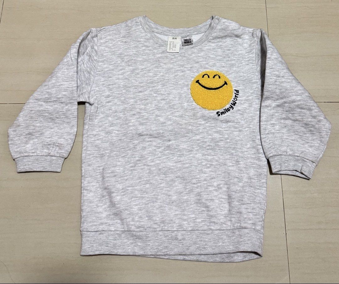 H&M SmileyWorld children's sweatshirt (Category: Babies & Kids Fashion) located in Quezon City. Submitted by andanel16 (Listing ID 1466846884, Image 1). Description: H&M SmileyWorld children’s sweatshirt featuring a textured yellow smiley face patch on the chest. Kids Clothes Declutter/ Preloved Baby Boy Clothes (24 mos) These are preloved/declutter items, so please manage your expectations. Minor signs of use may be present due to previous wear.