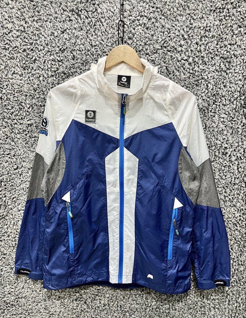 Hummel Hyper Technical colorblock windbreaker jacket. | Size L (Category: Coats, Jackets and Outerwear) located in General Trias. Submitted by zrchustle.604 (Listing ID 1466970582, Image 1). Description: Hummel Hyper Technical colorblock windbreaker jacket. It features a prominent blue, white, and gray geometric panel design, a full-zip front closure, zippered hand pockets with bright blue contrast trim, and a high collar that houses a packable h