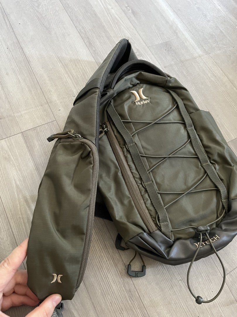 Hurley Olive Green Crossbody Bag (Category: Sling Bags) located in Subic. Submitted by yuridecluttersxz (Listing ID 1466808145, Image 3). Description: Hurley Crossbody Bag in Olive Green - Brand: Hurley - Color: Olive green - Condition: with small rip - Compartments: Zippered main compartment with inner slip and mesh zip pockets - Exterior: Front pocket with cord bungee system - Strap: Adjustable and padded, featuring a small attached zippered po