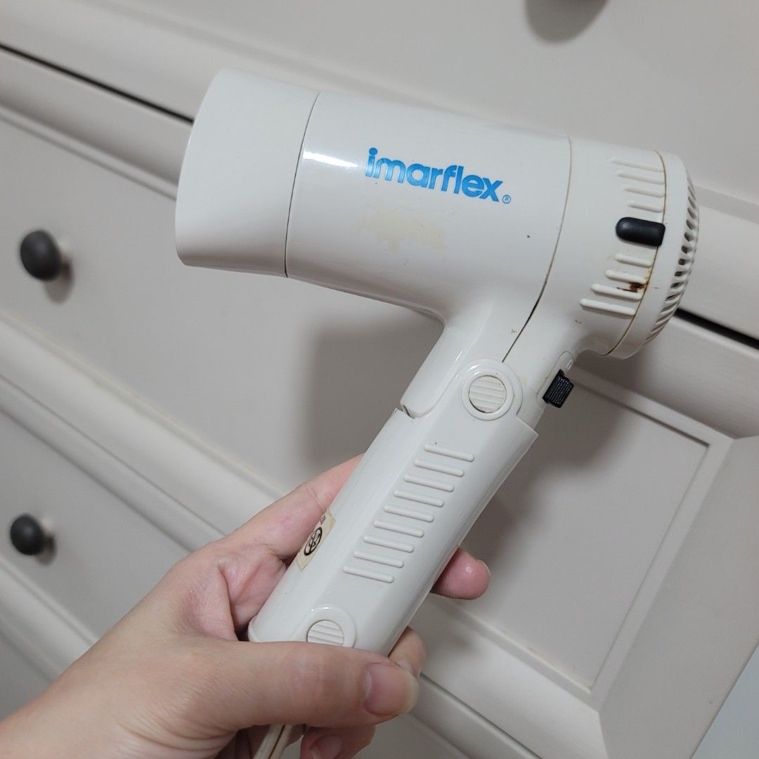 Imarflex Foldable Hair Dryer White (Category: Hair) located in Pasig City. Submitted by bunny.bella (Listing ID 1466923744, Image 1). Description: - Brand: Imarflex - Color: White - Design: Compact size with a convenient foldable handle, ideal for travel - Settings: Dual speed settings with an easy-to-use black switch - Condition: Fully functional and powers on well, with normal signs of use and slight body discoloration - Features: Circular rear