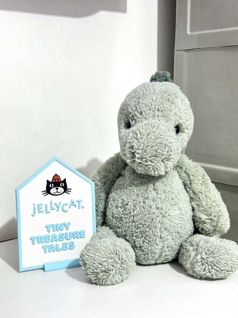Jellycat Puffles Dino Medium (Category: Plushies & Soft Toys) located in Cabanatuan. Submitted by tinytreasuretales (Listing ID 1466878188, Image 2). Description: - Brand: Authentic Jellycat - Character: Sage Green Dinosaur plush toy - Condition: Clean fabric, well-kept, like new - Features: Soft textured fur, dark green tuft of hair on top, huggable size - Tag: Original brand tag securely attached - Perfect for: Gifts, collectors, and kids.