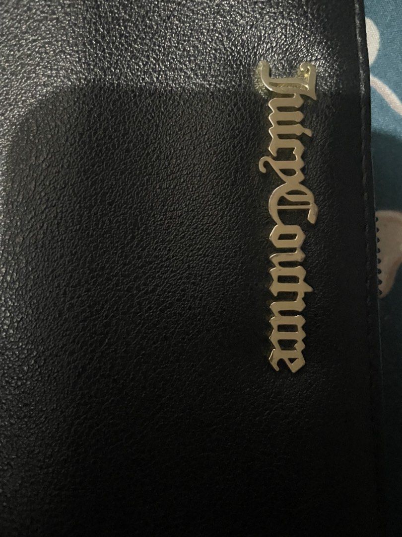Juicy Couture Black Zip Around Wallet (Category: Wallets & Card holders) located in Manila. Submitted by uiiauiiauiauiiaui (Listing ID 1466838513, Image 3). Description: - Brand: Juicy Couture - Color: Classic Black with elegant gold-tone hardware - Design: Signature brand lettering plate on the front - Interior: Clean branded fabric lining - Organization: Multiple card slots, spacious bill compartments, and a secure zippered coin pocket - Condit