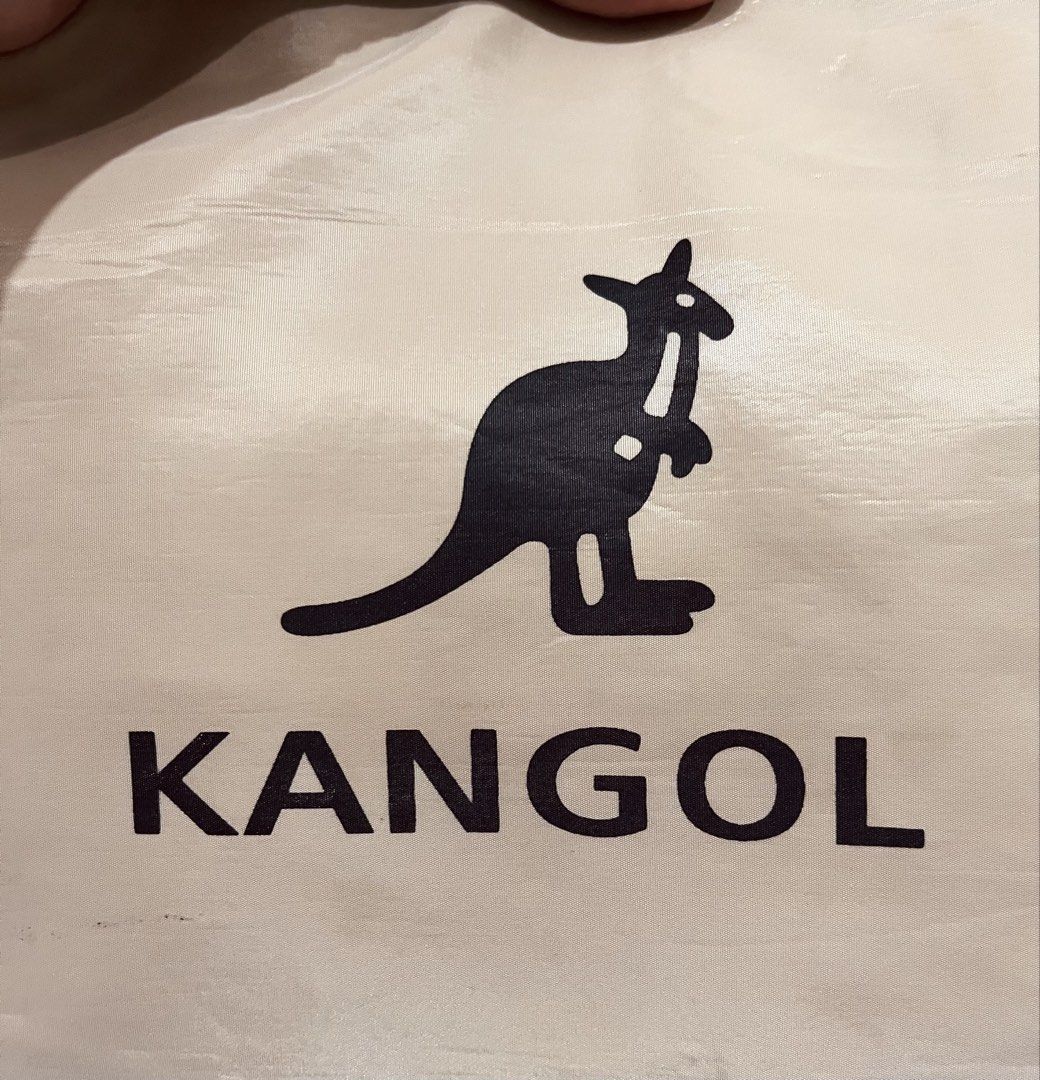Kangol beige nylon tote bag with drawstring (Category: Tote Bags) located in Talisay. Submitted by cherylu (Listing ID 1466937175, Image 2). Description: Beige Kangol tote bag in nylon material. Black kangaroo logo printed on the front. Drawstring closure mechanism at the top. Dual shoulder straps for carrying. Inside features a fabric brand patch and a zippered pocket. Spacious interior compartment with a structured bottom base..