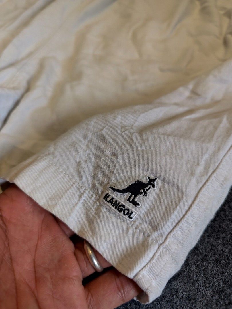Kangol White Drawstring Shorts Size XL (Category: Shorts) located in Cordova. Submitted by bsb.streetluxvintage.clothing (Listing ID 1466860399, Image 3). Description: - Brand: Kangol - Color: White - Size: XL - Waistband: Elastic with branded drawstring cords - Pockets: Two front pockets and one back pocket with button closure - Details: Embroidered kangaroo logo on the left leg hem - Condition: Comfortable casual wear, shows normal signs of pre