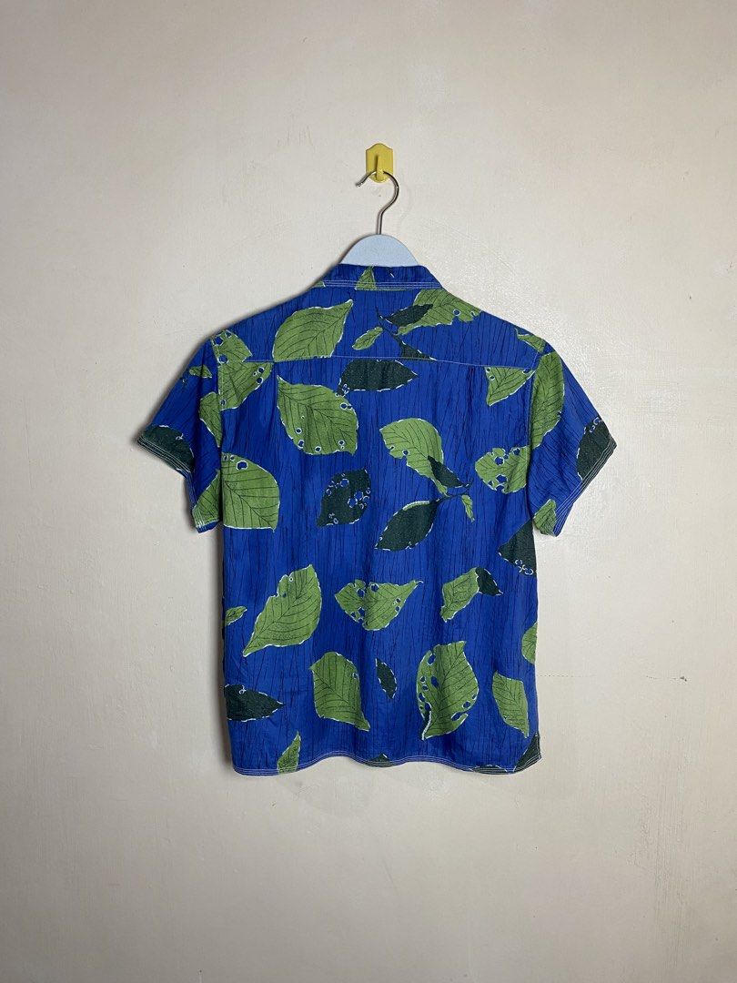KAPITAL Leaf Print Indigo Aloha Shirt (Category: Luxury Apparel) located in Naga. Submitted by dailyshipped (Listing ID 1466801992, Image 2). Description: It features Kapital’s signature indigo-dyed cotton base with a distinctive, graphic all-over print of green leaves designed with realistic “insect-bitten” detailing (mushikui). Key technical signatures of this garment include triple-stitch contrast needlework on the collar, four-track structura