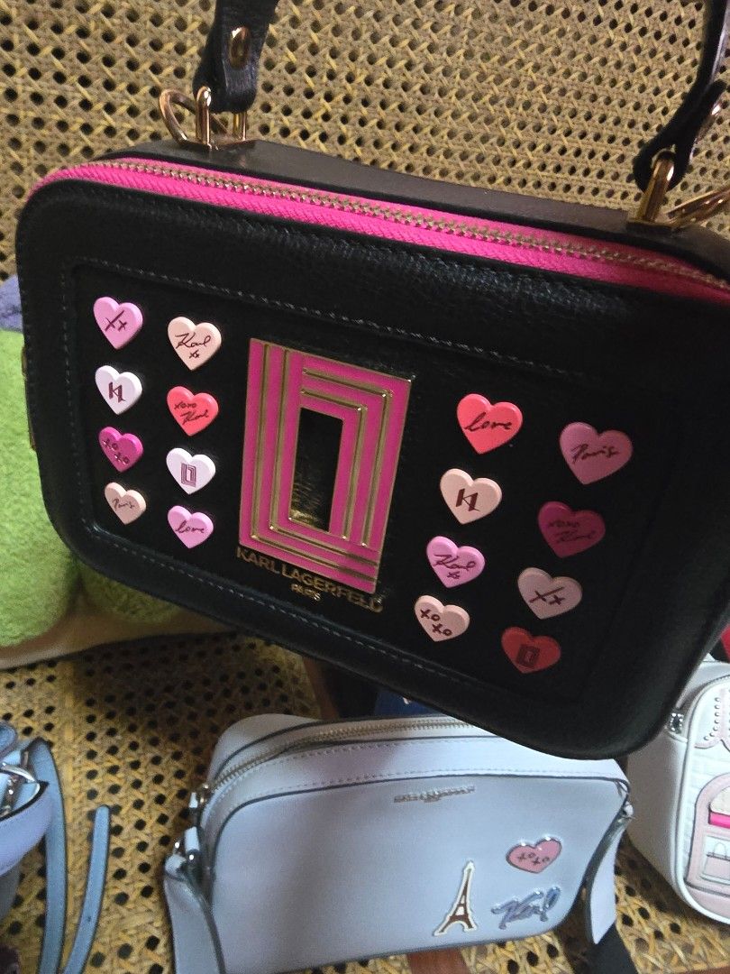 Karl Lagerfeld Black Heart Pattern Handbag (Category: Shoulder Bags) located in San Fernando. Submitted by banings (Listing ID 1466797865, Image 1). Description: - Brand: Karl Lagerfeld - Color: Black with pink/white heart embellishments - Details: Bright pink top zipper trim and gold-tone hardware/branding plaque - Structure: Structured shape with double black top handles - Condition: Excellent - Note: Other bags in photos shown for size referen