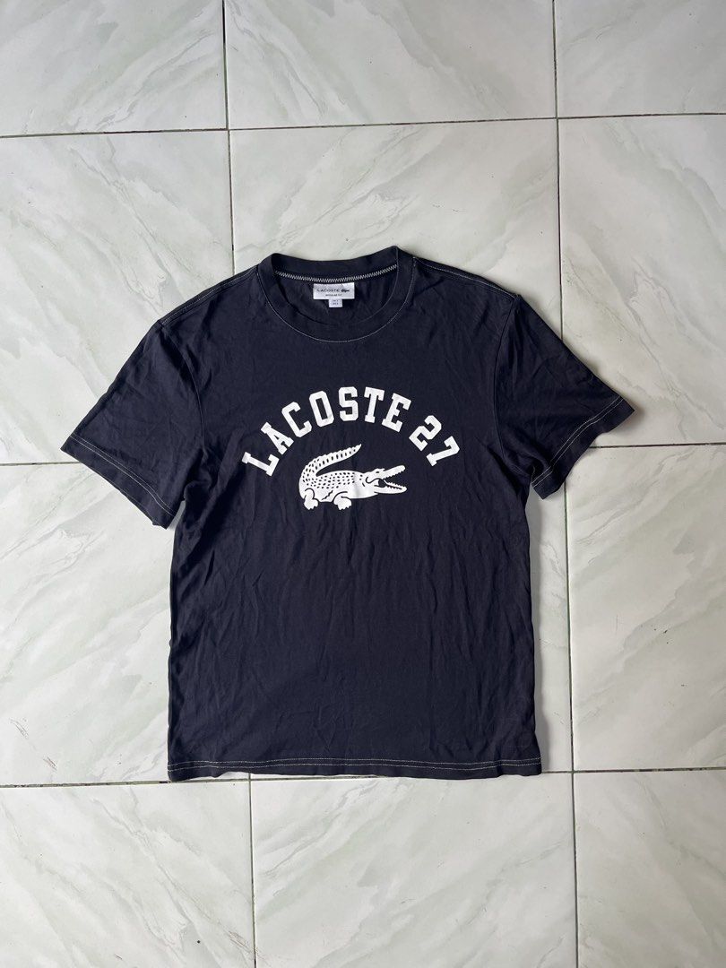 Lacoste 27 Black T-Shirt Regular Fit (Category: Tshirts & Polo Shirts ) located in Naga. Submitted by stoob.finds (Listing ID 1466800041, Image 2). Description: - Brand: Lacoste - Color: Black with white graphic and contrast stitching - Size: US Small (FR 3) - Fit: Regular fit - Design: Large 'Lacoste 27' chest print with classic crocodile logo and white accent stitching - Condition: Clean and ready to wear -Length 25 -width 18.5.