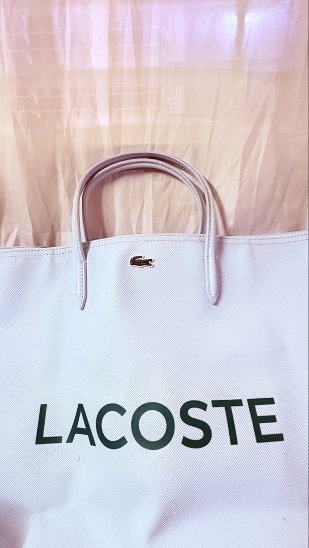 Lacoste Light Blue Canvas Tote Bag With Strap (Category: Tote Bags) located in Pateros City. Submitted by marifernandez (Listing ID 1466784261, Image 2). Description: - Preloved Authentic Lacoste canvas travelling tote bag in light blue - Features the iconic green Lacoste logo on the front and a metal crocodile badge near the top handles - Includes a matching turquoise shoulder strap with repeating Lacoste lettering - Interior comes with a practi