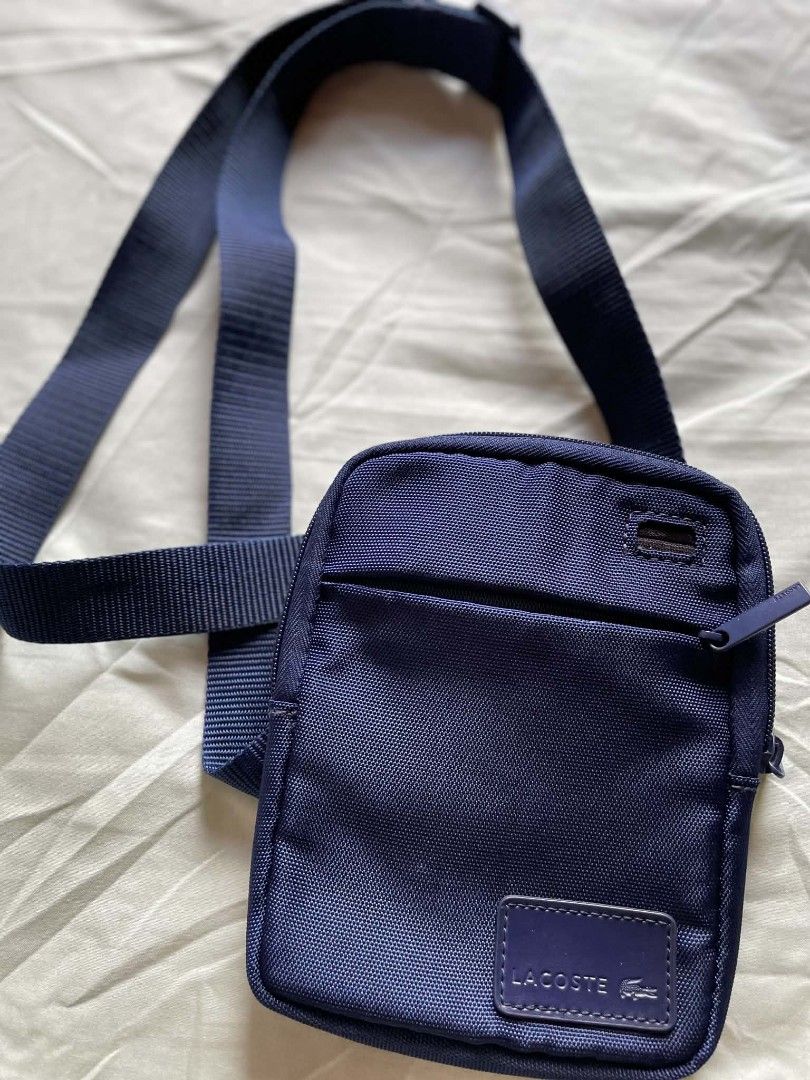 Lacoste Navy Blue Crossbody Bag (Category: Cross-body Bags) located in Manila. Submitted by xtinamendo00659 (Listing ID 1466836448, Image 2). Description: - Authentic navy blue Lacoste crossbody bag made from durable nylon - Adjustable shoulder strap for a comfortable, custom fit - Secure main compartment and front zip pocket with branded zipper pulls - Features the classic rectangular Lacoste logo patch on the front - Impeccably clean interior a