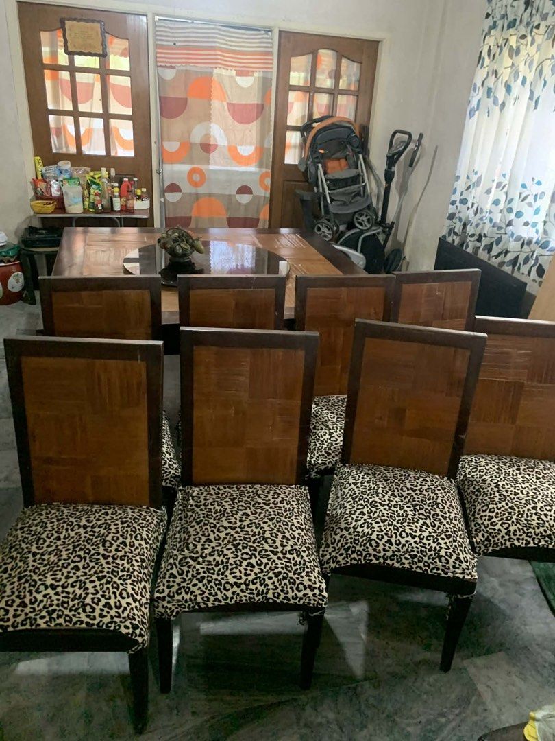 Large Wooden Dining Table with 8 Leopard Print Chairs (Category: Tables & Sets) located in Manila. Submitted by samsongarcia (Listing ID 1466889433, Image 2). Description: Big square wooden dining table with a dark brown outer frame, parquet top pattern, and a revolving black lazy Susan glass tray in the middle. Includes eight matching dining chairs with checkerboard wooden backs and leopard print fabric seats. Sturdy setup, seats a large family 
