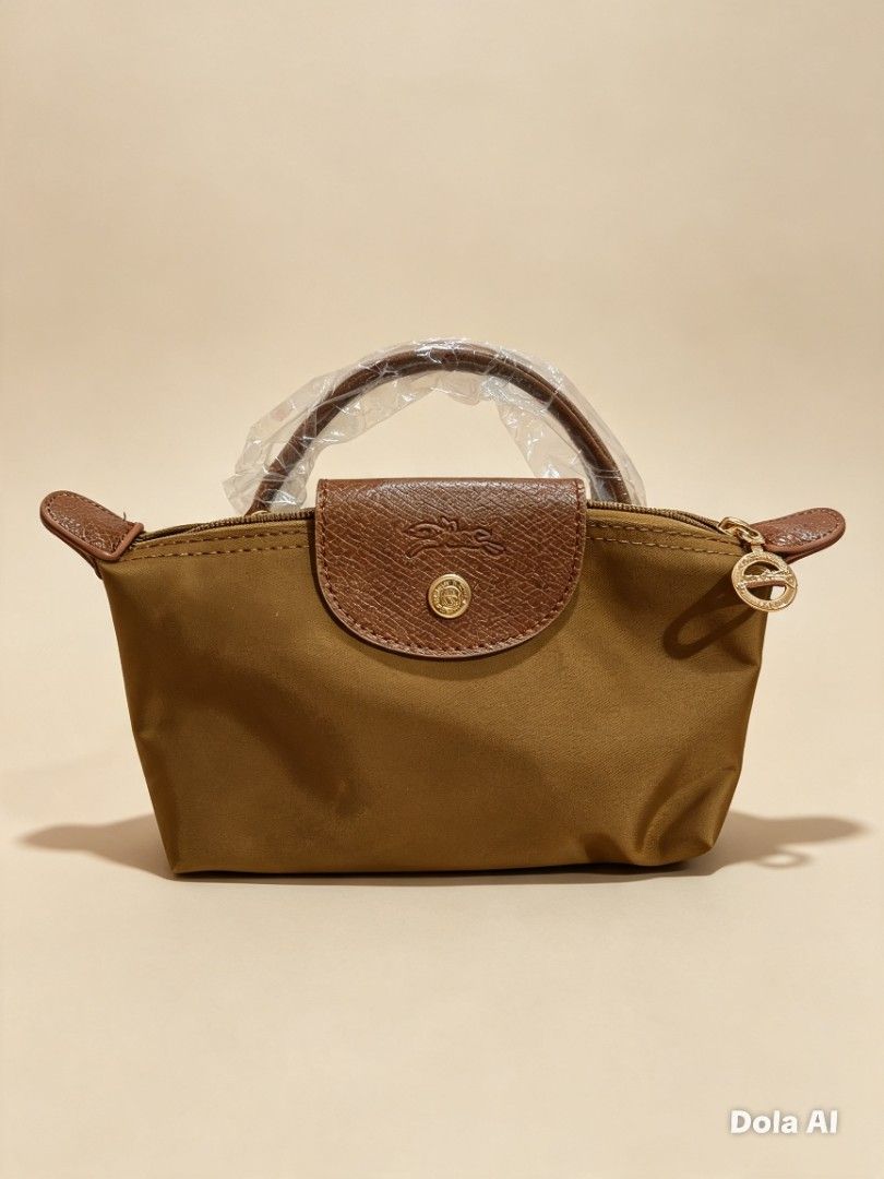 LC Mini Nylon Top Handle Bag with sling strap (Category: Luxury Bags & Wallets) located in Makati City. Submitted by sweet21onlineshoppe (Listing ID 1466807779, Image 2). Description: - Longchamp Le Pliage mini pouch handle bag - Color: Navy blue nylon body with signature brown leather trim - Hardware: Gold-tone hardware with secure snap button closure - Condition: Brand new, top handle still wrapped in original plastic protection - Features: Smo