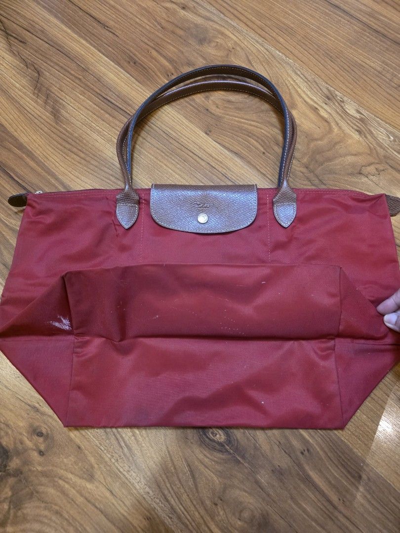 Longchamp Le Pliage Red Tote Bag (Category: Luxury Bags & Wallets) located in Iligan City. Submitted by ilovechocolatecakes (Listing ID 1466777646, Image 2). Description: - Authentic Longchamp Le Pliage tote bag in classic red - Brown leather handles and flap with zip top and snap button closure - Spacious interior with a convenient slip pocket - Perfect daily carryall for work, school, or travel - Condition note: Shows normal signs of wear with 