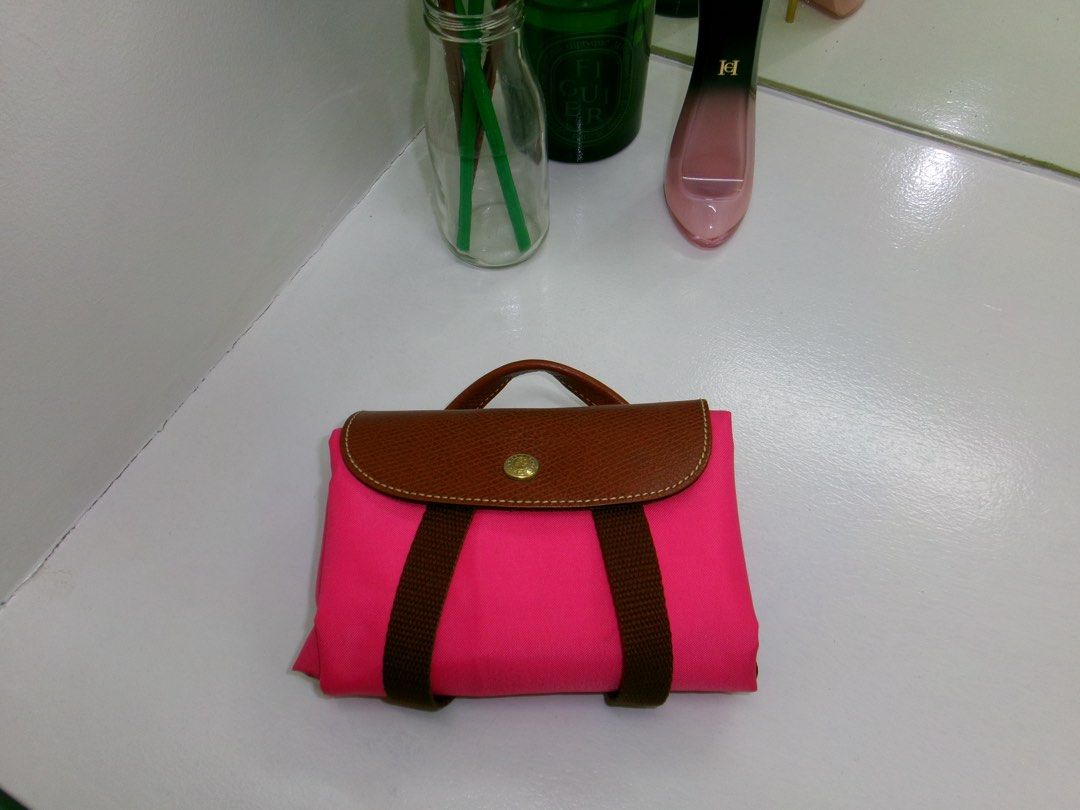 Longchamp Pink Backpack (Category: Luxury Bags & Wallets) located in Marikina City. Submitted by sheclothesandstilettos (Listing ID 1466863499, Image 2). Description: - Material: Durable pink nylon with stylish brown leather top flap - Closure: Secure snap button closure with adjustable brown straps - Capacity: Easily fits a tablet or small laptop (yellow case shown for scale) - Versatility: Adds a great pop of color for everyday errands or schoo