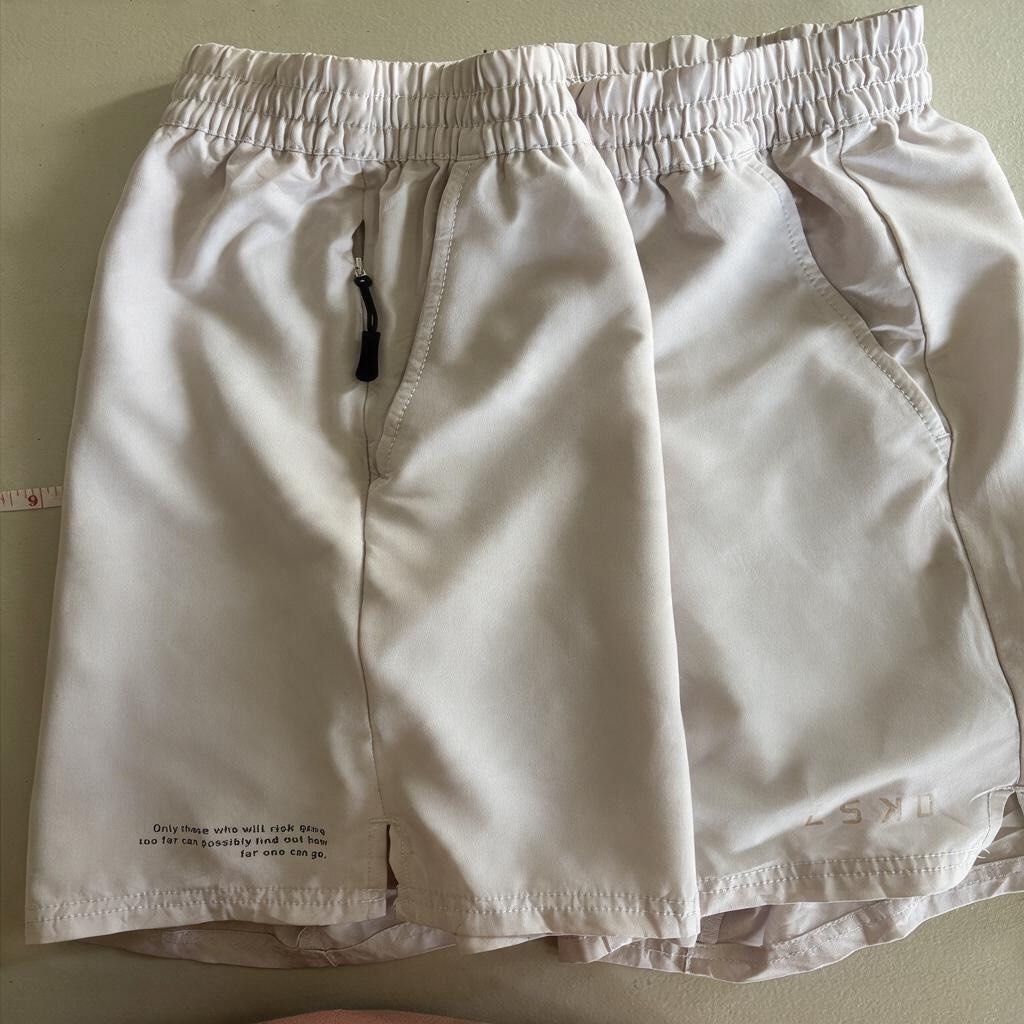 LSKD running shorts (Category: Activewear) located in Iloilo. Submitted by oddforest.c9c7d5 (Listing ID 1466809497, Image 1). Description: - Brand/Model: LSKD Athletic Shorts - Size: MED-LARGE - Color: Light Grey with black drawstring - Material: Lightweight technical fabric - Features: Secure zipped side pockets & elastic waistband - Detail: Small motivational quote printed near the hem - Condition: Clean, great for workouts or casual wear.