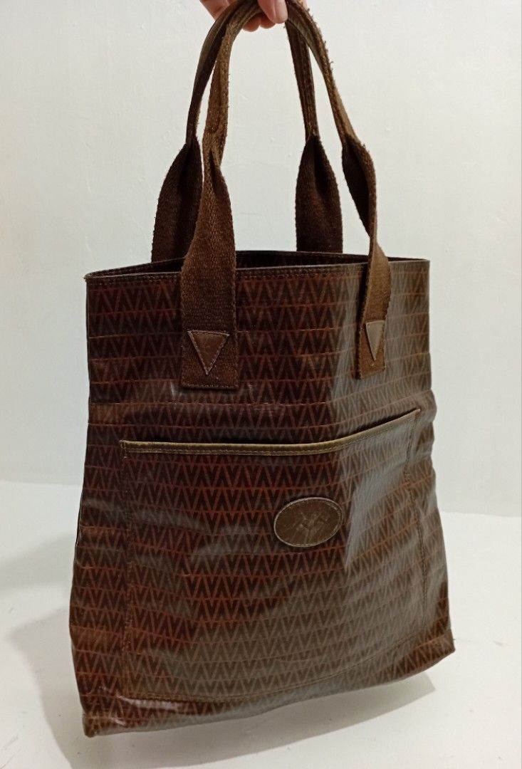 Mario Valentino Brown V-Pattern Large Tote Bag (Category: Luxury Bags & Wallets) located in Navotas City. Submitted by riyuwi (Listing ID 1466860885, Image 1). Description: PreOwned Lightly Used Mario Valentino brown tote bag - Stylish repeating V pattern on durable coated material - Double fabric handles for comfortable shoulder or hand carry - Convenient front exterior pocket with branded oval patch - Spacious interior lined with brown textile 