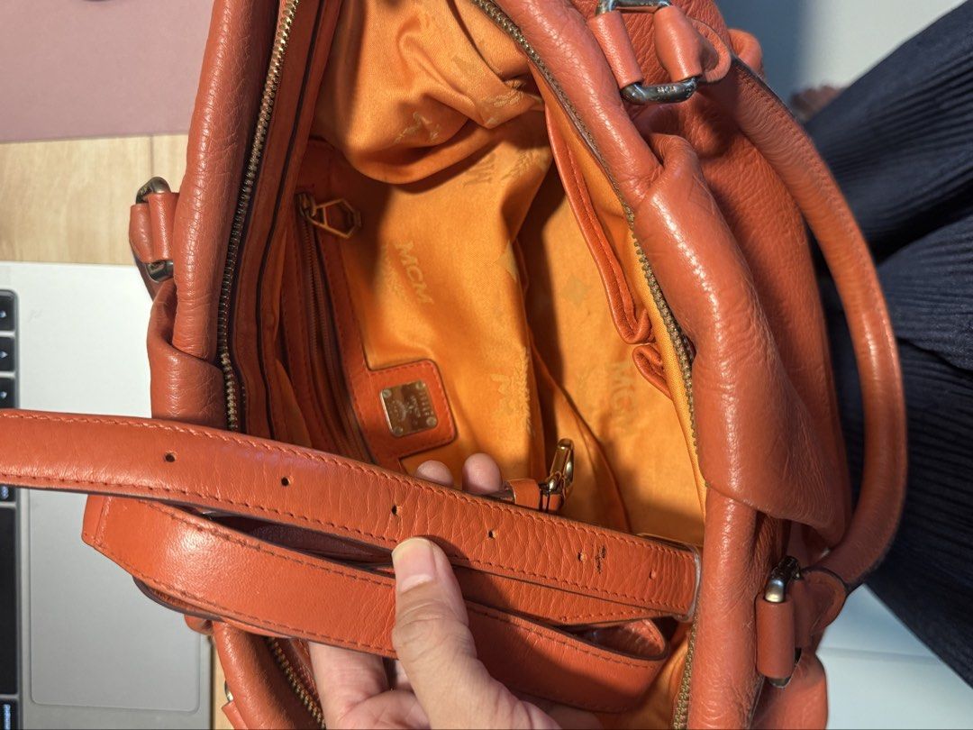 MCM Orange Leather Tote Shoulder Bag (Category: Luxury Bags & Wallets) located in Cebu City. Submitted by declutterbarbie_ (Listing ID 1466822025, Image 3). Description: Orange textured leather handbag from MCM. Stamped monogram pattern all over. Dual top handles plus a detachable shoulder strap. Gold tone hardware and logo plaque on front. Bright orange fabric interior lining includes zip pockets and slip compartments. Roomy everyday tote design