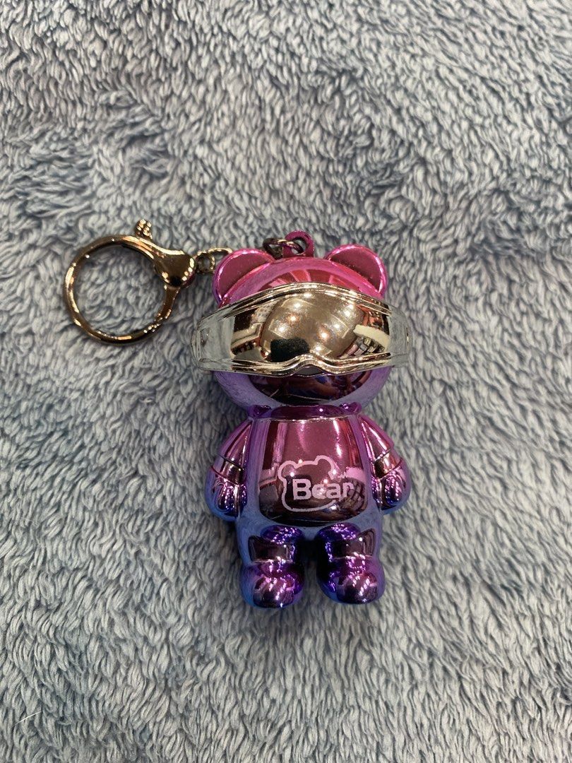 Metallic Purple Bear Keychain with Visor (Category: Character Goods) located in Manila. Submitted by j9e0fri_2025 (Listing ID 1466948045, Image 1). Description: - Purple and pink metallic finish - Features silver futuristic visor glasses and chest logo - Equipped with a sturdy swivel clasp - Perfect for keys, backpacks, and bags - Has a light when you open the visor - Batteries need to be replaced.