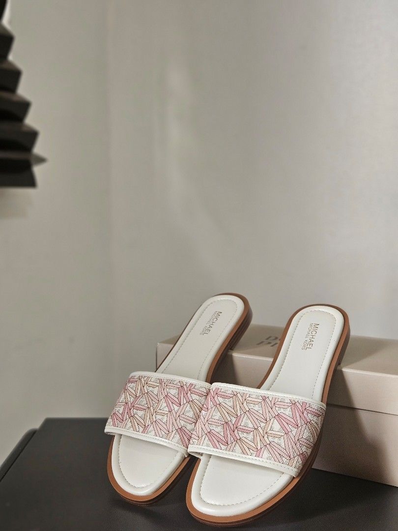 Michael Kors Dana Slides Sandals (Category: Flats & Sandals) located in Quezon City. Submitted by angelafrancescarasos (Listing ID 1466922006, Image 2). Description: - Brand: Michael Kors - Style: Dana slides / slip-on sandals - Size: 6.5 US Women's - Color: White base with pink geometric pattern - Condition: Brand new, never worn, pristine (no box) - Features: Flat sole, MK logo on insole and embossed on bottom - Perfect for: Warm weather and ca