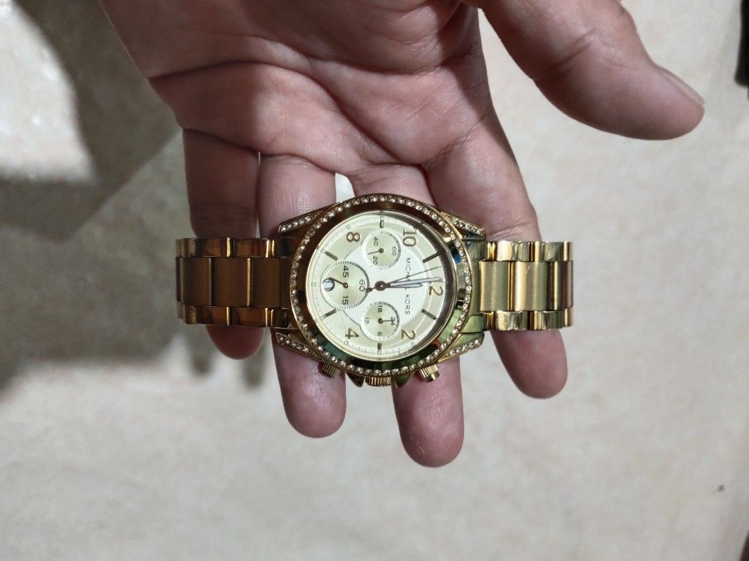 Michael Kors Gold Chronograph Watch with Crystals (Category: Women's Watches) located in Manila. Submitted by az272019 (Listing ID 1466909833, Image 3). Description: - Brand: Michael Kors - Color/Finish: Elegant gold-tone with a matching champagne dial - Features: Crystal-embellished bezel, chronograph function with 3 sub-dials, numeral markers, and MK-engraved crown - Band: Standard metal link bracelet with a secure fold-over clasp - Inclusions: