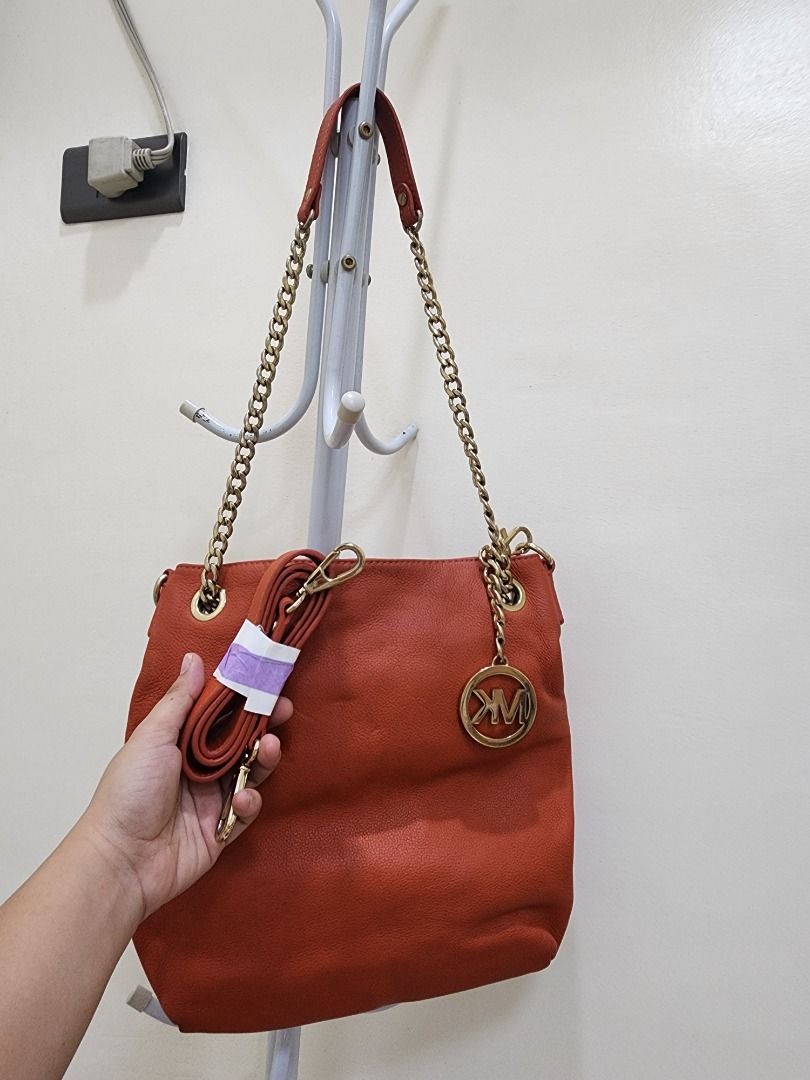 Michael Kors Orange Leather Shoulder Bag with Chain Strap (Category: Luxury Bags & Wallets) located in Caloocan City. Submitted by keenmoon.752ef0 (Listing ID 1466938475, Image 1). Description: - Brand/Model: Authentic Michael Kors leather handbag - Color: Bright orange with shiny gold-tone hardware - Material: Soft and durable pebble leather - Features: Signature MK logo charm and chain straps - Strap: Extra long strap rolled up and attached in 