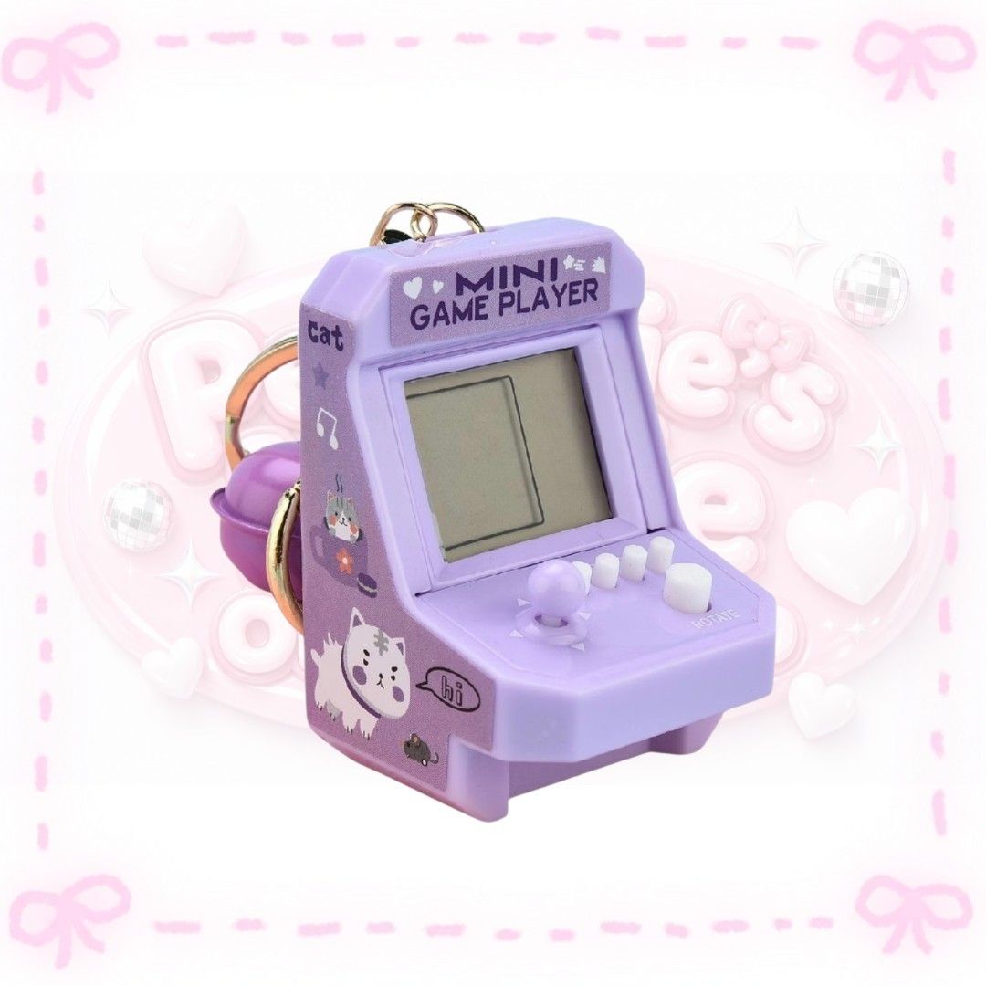 Mini Game Player Arcade Keychain with Cat Graphics (Category: Character Goods) located in Sorsogon. Submitted by mitchelle0425 (Listing ID 1466941397, Image 1). Description: - Purple mini arcade game console keychain with retro handheld design - Features a tiny working joystick, buttons, and classic digital screen graphics - Adorable side art showing cute white and grey cats with mice - Compact and lightweight, perfect for decorating keys, backpa
