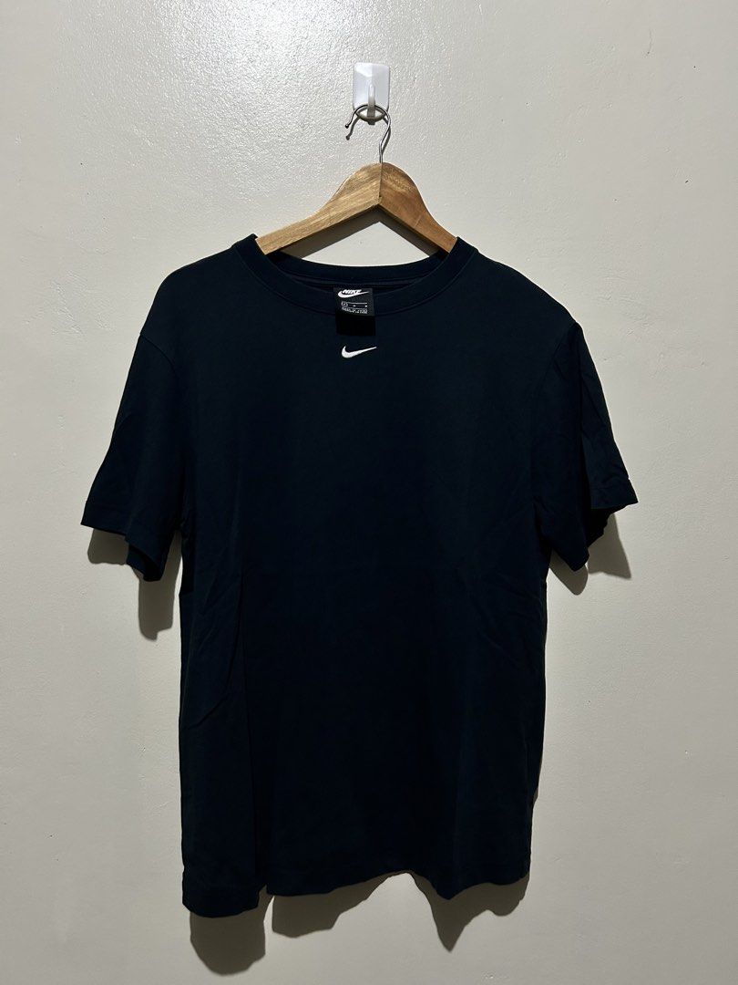 Nike Centered Swoosh Black T-Shirt (Category: Tshirts & Polo Shirts ) located in Angeles City. Submitted by johngamboa (Listing ID 1466961971, Image 1). Description: - Brand: Nike - Color: Classic Black - Design: Small white embroidered swoosh below the front collar - Fit: Regular/Standard fit with crew neck and short sleeves - Condition: Clean and well-maintained - Best for: Everyday casual wear, gym, or workouts - Modesty/Style: Minimalist and 