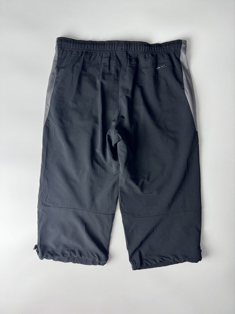 Nike Dri-FIT Black Capri Track Pants (Category: Shorts) located in Manila. Submitted by babygirly2k (Listing ID 1466875621, Image 3). Description: Nike Dri-FIT track pants in black, cropped capri length. Grey mesh panels running down the sides. Elastic waistband with a snap button closure. Adjustable drawstrings at the hem to switch up the fit. Embroidered white swoosh logo near the pocket. Lightweight athletic material. Back pocket features a sm