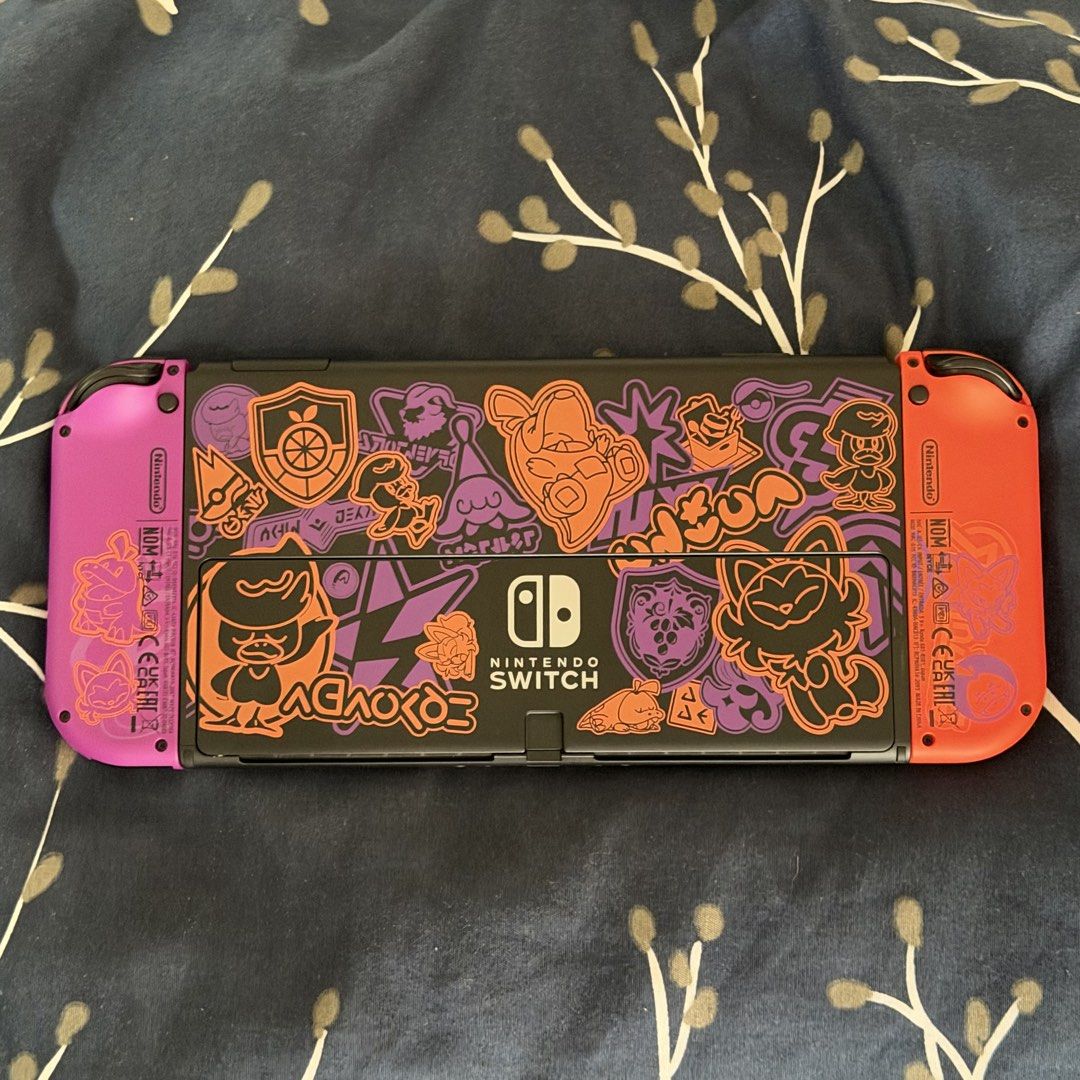 Nintendo Switch OLED Model Pokémon Scarlet & Violet Edition (Category: Nintendo) located in Taguig. Submitted by traderfromsouth (Listing ID 1466805150, Image 2). Description: - Special Edition Nintendo Switch Scarlet & Violet handheld console - Vibrant orange and purple Joy-Cons featuring academy crests - Custom graffiti-style artwork and starter Pokémon printed on the black back casing - Handheld console only NON JB / TEST ALL U WANT UPON MEETU