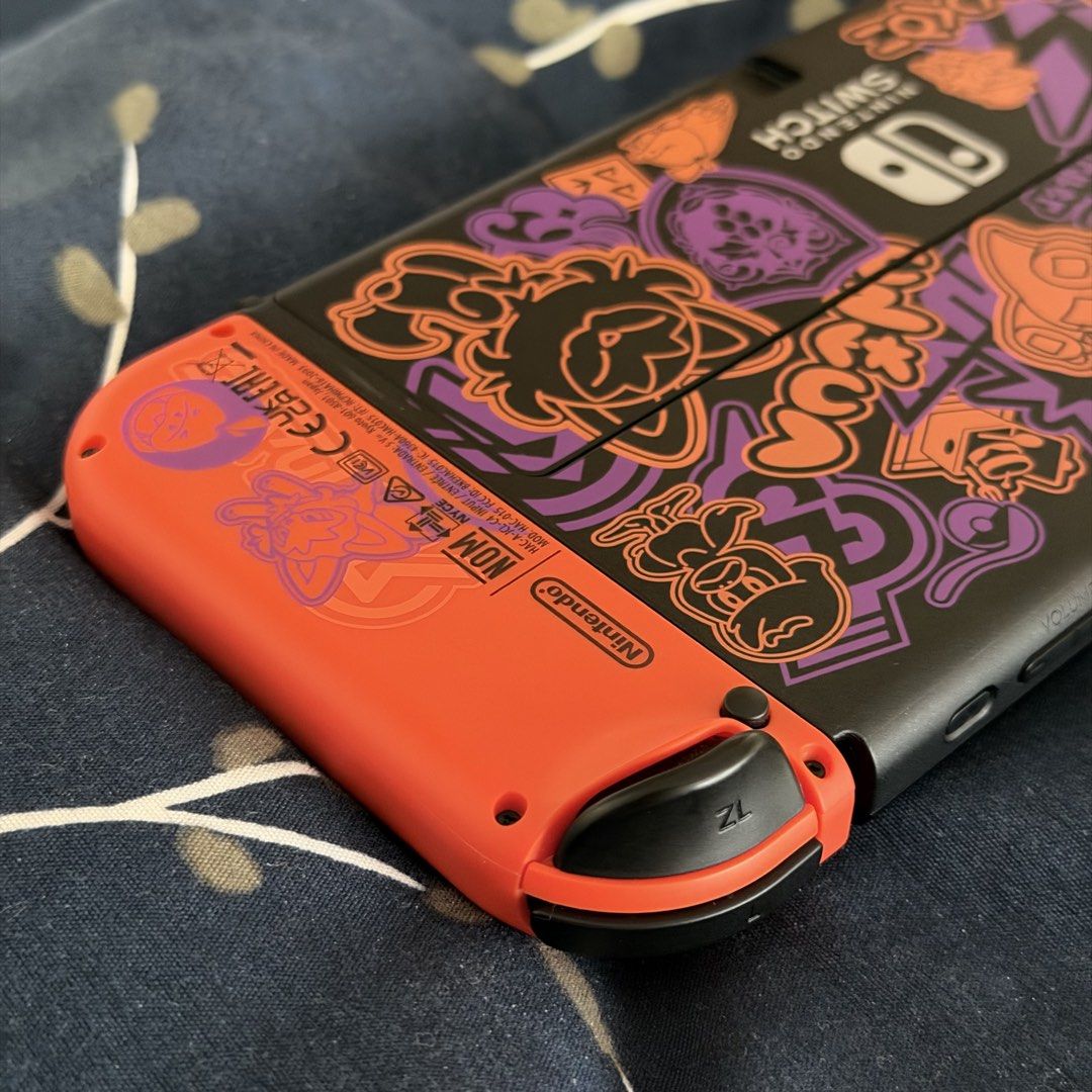 Nintendo Switch OLED Model Pokémon Scarlet & Violet Edition (Category: Nintendo) located in Taguig. Submitted by traderfromsouth (Listing ID 1466805150, Image 3). Description: - Special Edition Nintendo Switch Scarlet & Violet handheld console - Vibrant orange and purple Joy-Cons featuring academy crests - Custom graffiti-style artwork and starter Pokémon printed on the black back casing - Handheld console only NON JB / TEST ALL U WANT UPON MEETU