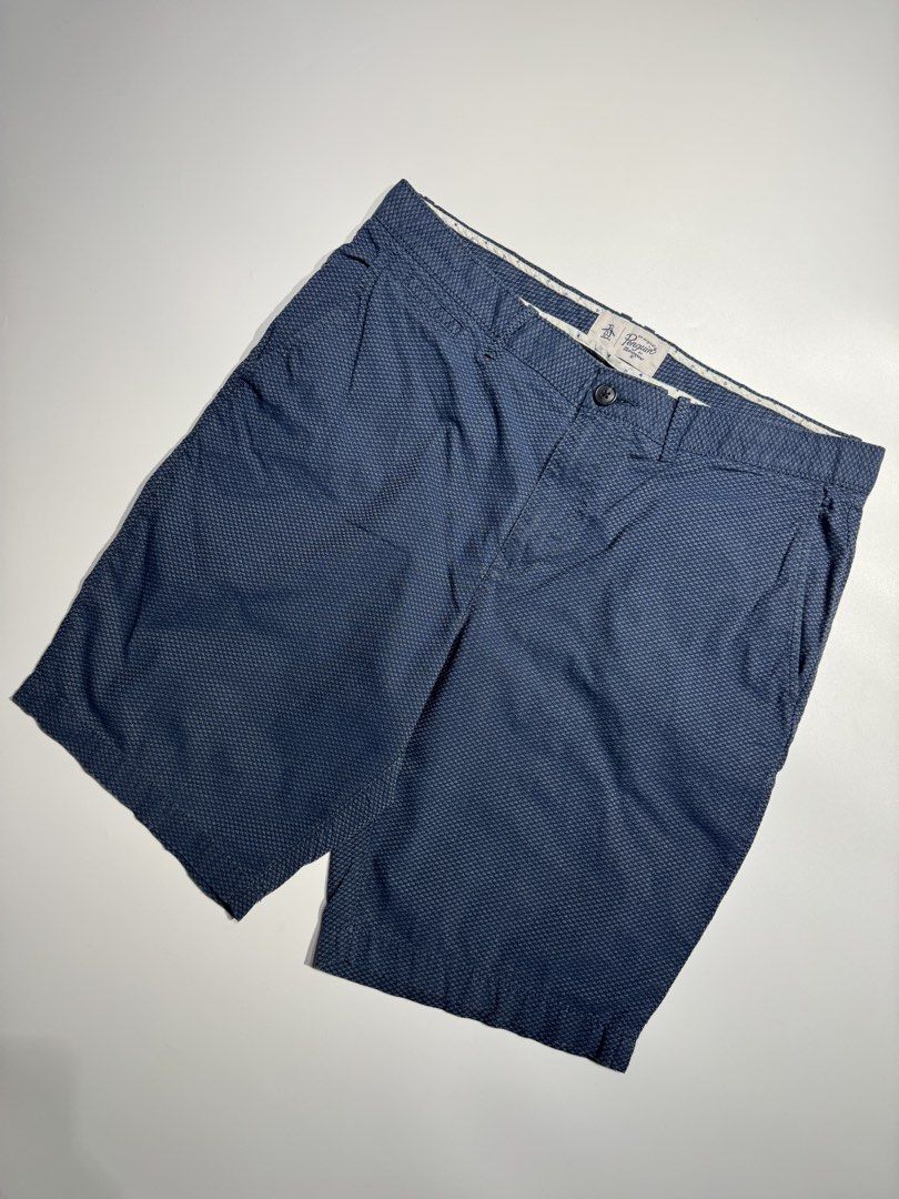 Original Penguin Blue Patterned Shorts (Category: Shorts) located in Cavite. Submitted by dracokidstuff (Listing ID 1466873189, Image 3). Description: - Brand: Original Penguin - Color: Dark Blue with textured geometric pattern - Measurements: 17 inches across waist, 21 inches outseam length - Closure: Button closure and zip fly - Pockets: Front hand pockets and two buttoned rear pockets - Details: Stylish patterned fabric lining along the interi